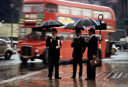 Yağış yağarkən London küçəsində dayanan üç centlmen. Böyük Britaniya, 1964-cü il