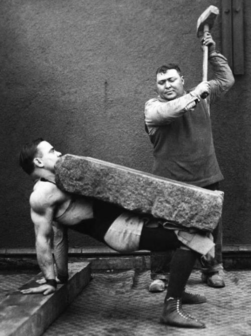 Bir adam pəhləvanın bədənində olan daş lövhəsinə vurur, 1930-cu il