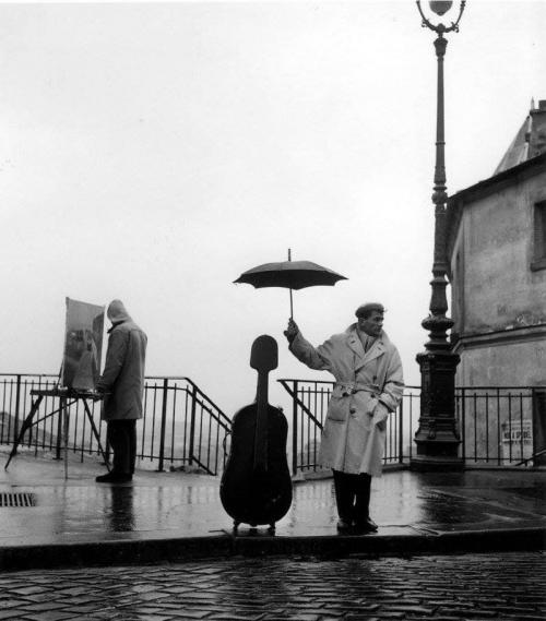 Kişi violonçelini yağışdan qoruyur. Paris, 1957-ci il
