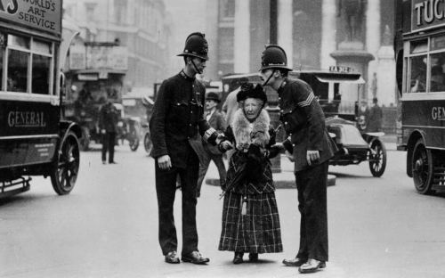 Polislər yaşlı qadına küçəni keçməyə kömək edirlər. London, 1910-cu il